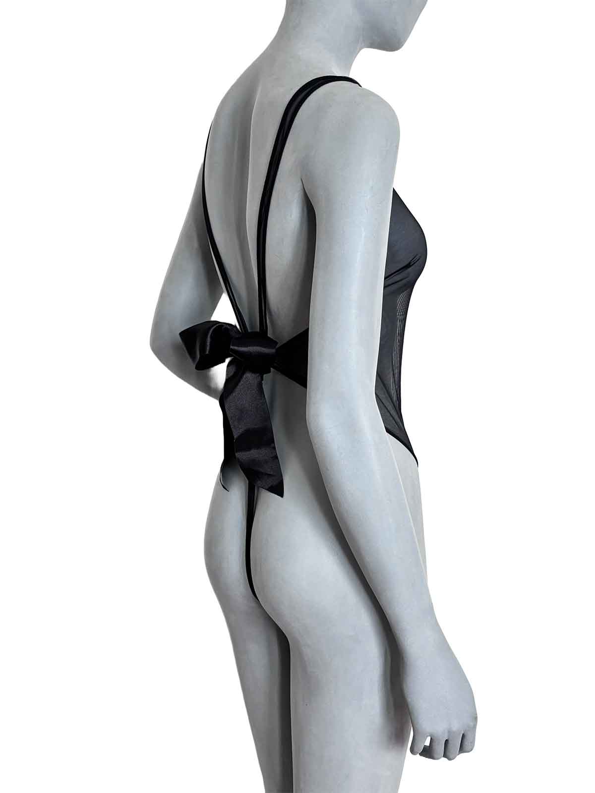 Vista lateral do body Beatriz Cisô em tule transparente preto com laço de cetim nas costas e design fio dental