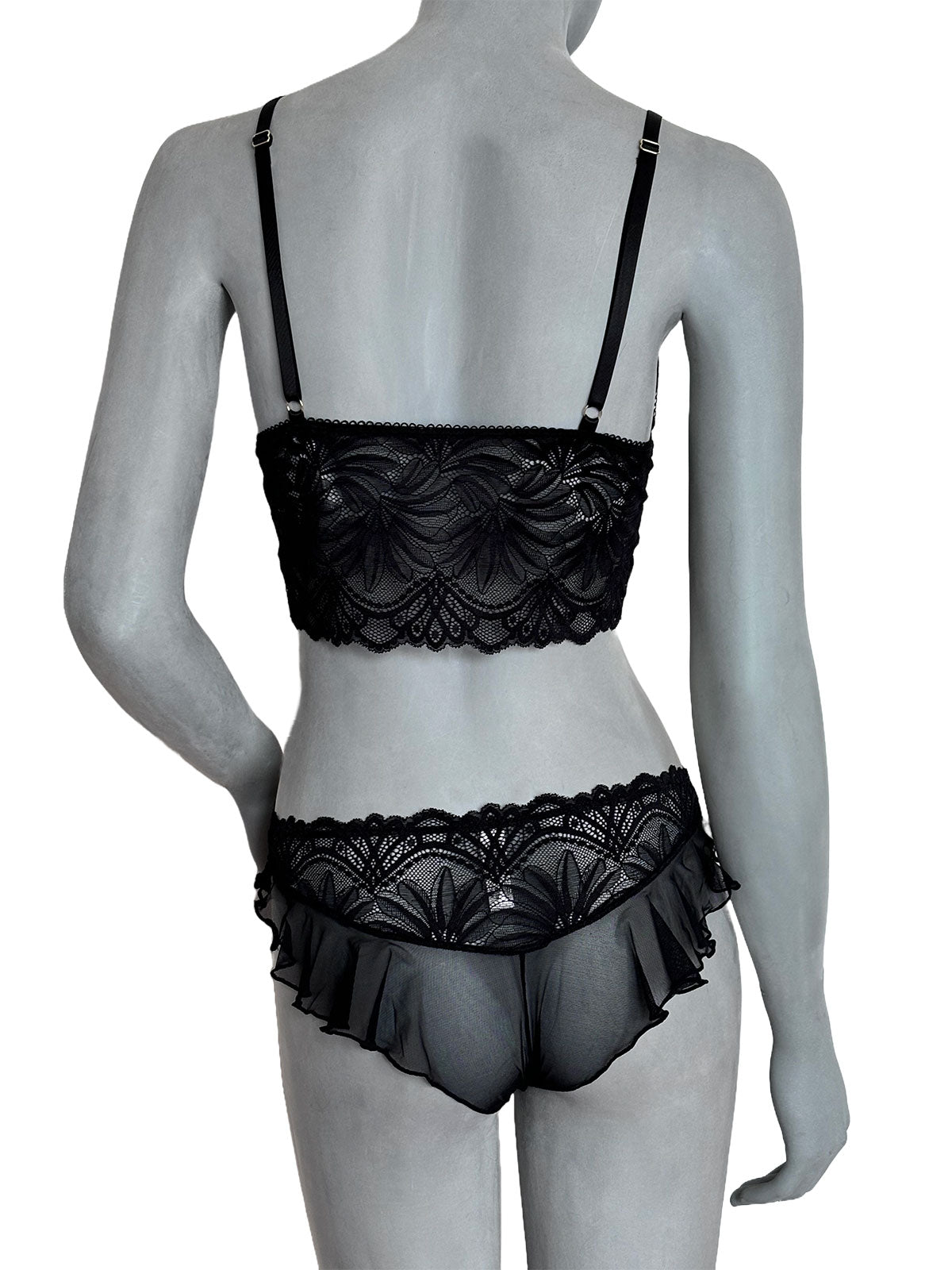 Sutiã Kamila preto em renda floral, alças finas pretas ajustáveis, calcinha preta em tule com renda floral e babado, vista costas completa em manequim fundo neutro, conjunto lingerie sem bojo artesanal Cisô Atelier
