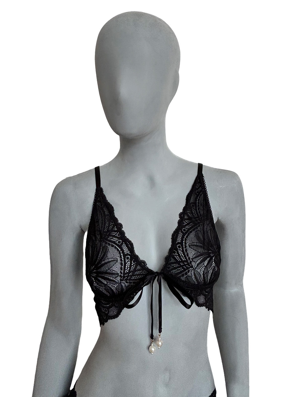 Sutiã Kamila preto em renda floral, decote profundo triangular com laço e fecho frontal (central) e pingentes de pérolas, alças finas pretas ajustáveis, vista frontal em manequim fundo neutro, lingerie sem bojo confortável design autoral Cisô Atelier