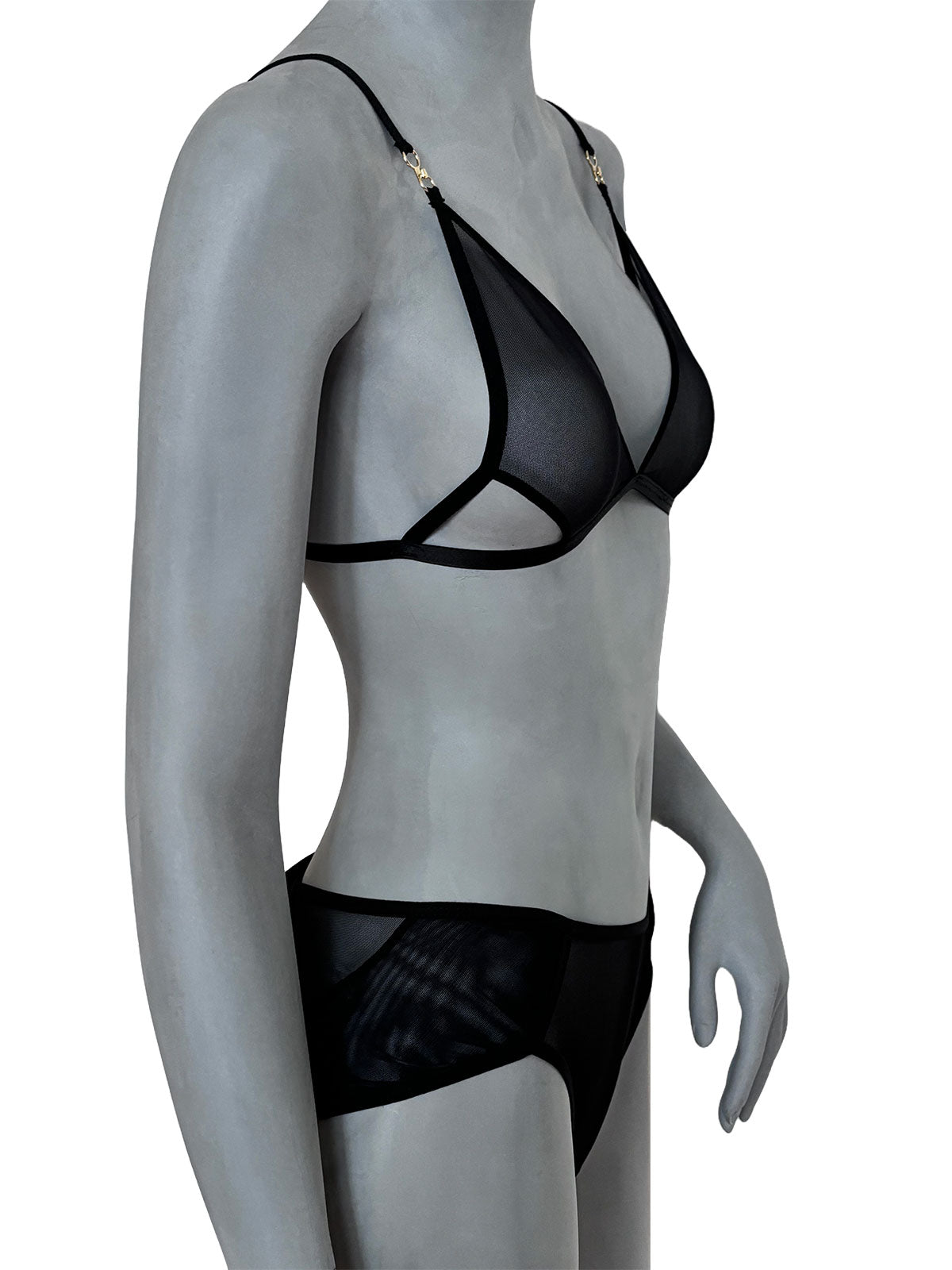 Sutiã Lauren preto em tule transparente com decote triangular profundo e tiras cruzadas, alças finas pretas com abertura e ajustáveis com fechos dourados, calcinha preta em tule, vista lateral em manequim fundo neutro, conjunto lingerie sem bojo artesanal Cisô Atelier