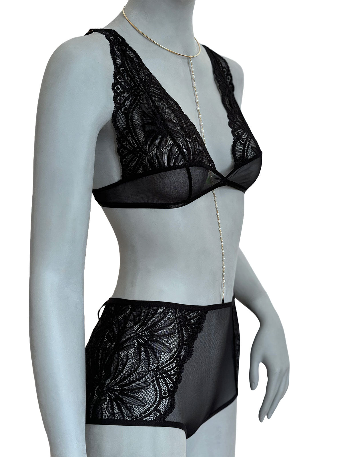 Sutiã Elissa preto com renda floral em tule transparente e calcinha preta com renda lateral, manequim usando colar banhado em ouro com corrente e pingentes, vista lateral, conjunto lingerie artesanal Cisô Atelier