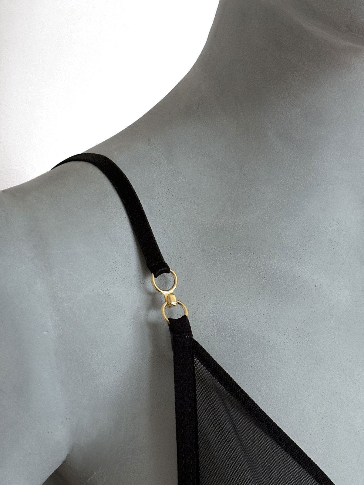 Sutiã Lauren preto em tule transparente, detalhe da alça fina preta ajustável com fecho e anel dourado, vista lateral em manequim fundo neutro, lingerie sem bojo artesanal Cisô Atelier